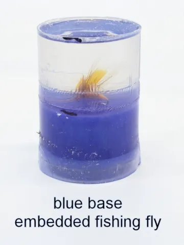 Bottle stopper blank with an embedded fishing fly over a blue base