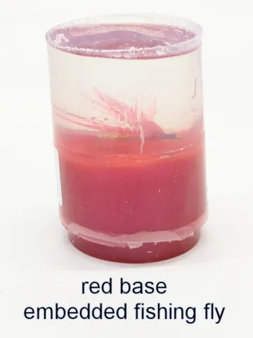 Bottle stopper blank with an embedded fishing fly over a red base