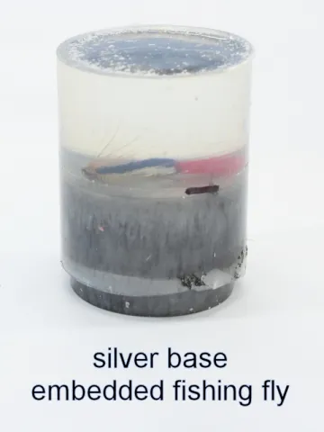 Bottle stopper blank with an embedded fishing fly over a silver base